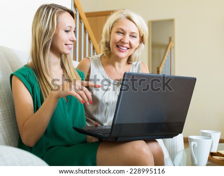 Smiling daughter teaching mother to computer using