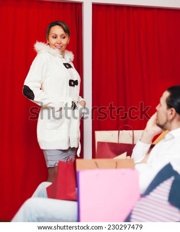 Couple choosing coat in fitting-room at fashion store