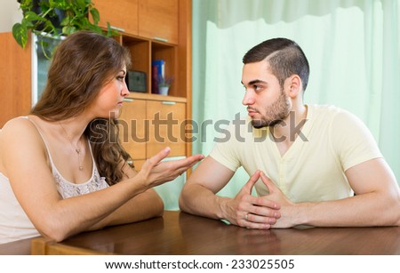 Young family having serious talking at the table in home