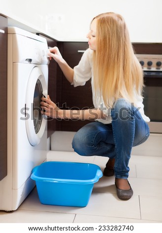 long-haired huosewife doing laundry with washing machine at home