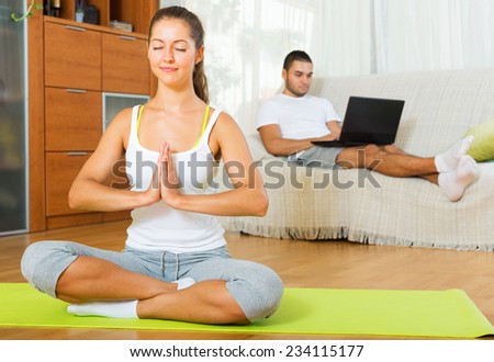 girl in yoga position and lazy guy on sofa at home