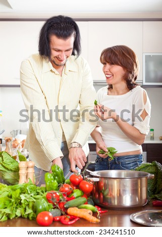 Young  happy couple cutting the celery for salad in kitchen
