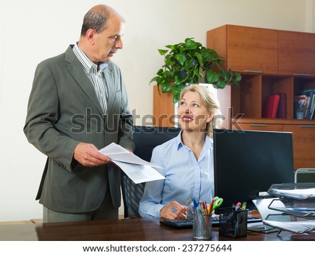 Ordinary office scene with two mature and positive co-workers