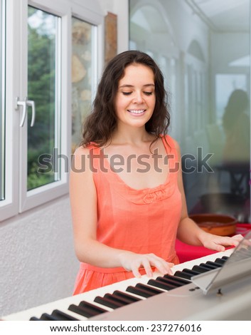 Beauty woman playing piano at home and smiling