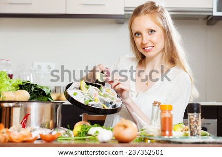 Smiling woman putting pieces lemon in fish