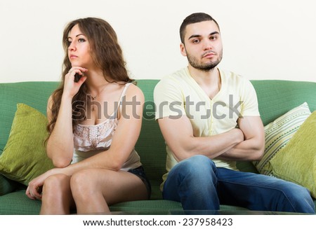 Unhappy guy and sad girl after quarrel in living room