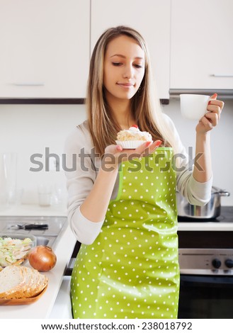 Woman in apron with cakes and tea in home kitchen