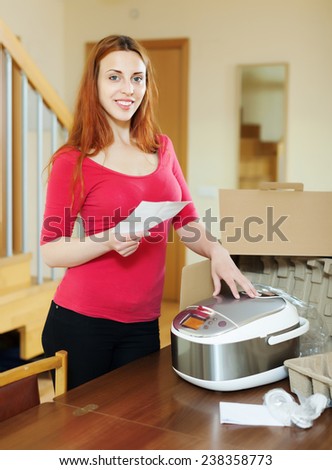 cheerful woman  reading guarantee card for new slow cooker at home