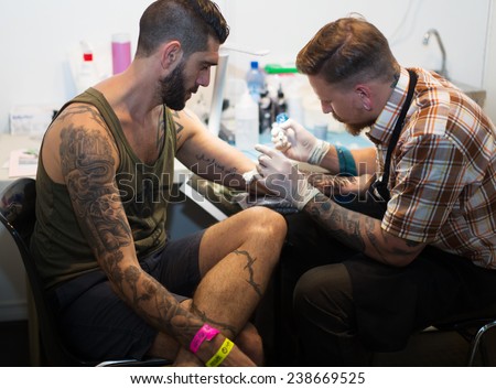 BARCELONA, SPAIN - OCTOBER 3, 2014: Professional artist  doing  tattoo on client arm. The 17th edition of The Barcelona Tattoo Expo