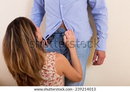 Young woman unbuckling the belt of man pants