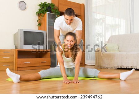Young couple doing regular exercises together in  house