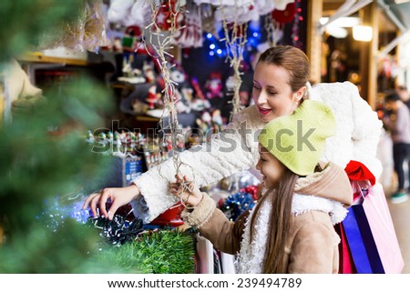 Happy woman with little daughter buying gifts at Christmas market. Focus on mother