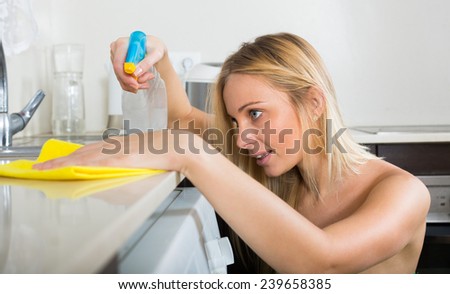 housewife cleaning furniture in domestic kitchen