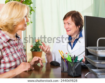 Smiling mature female doctor consulting patient in office