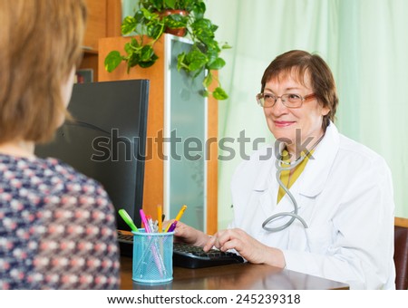 Elderly doctor communicates with patient sitting at PC