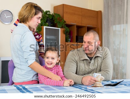 Wife, husband and two their children having a quarell about money at the table at home indoors