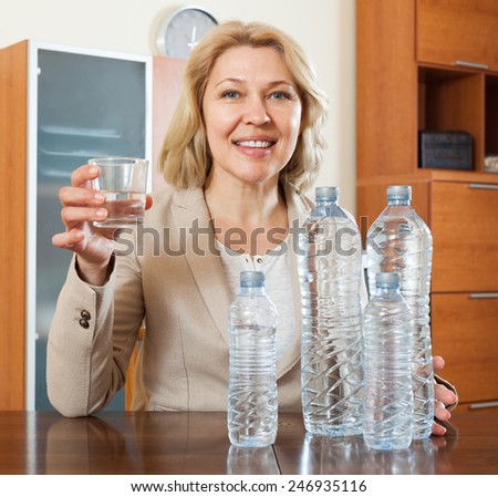 Happy mature woman with grass of water in home