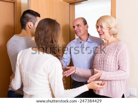 Positive young couple inviting elderly parents to come inside