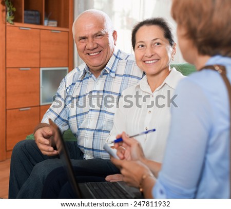 Mature couple answer questions of caseworker with computer in home