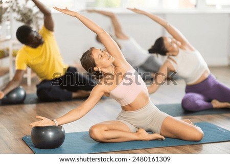 Similar – Image, Stock Photo Group of calm focused women and men practicing yoga with trainer standing in balance pose and stretching body in studio