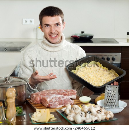 Young handsom man cooking french-style meat in the kitchen at home