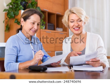 Mature women working with documents and smiling. Focus on brunette