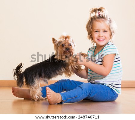 Happy cute little girl playing with Yorkshire Terrier indoor
