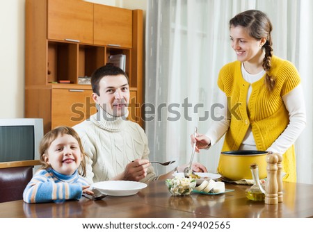 Happy family of three having lunch at home