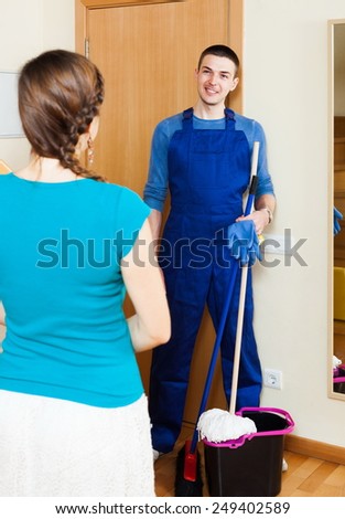 Housewife meeting smiling cleaner at the door at home