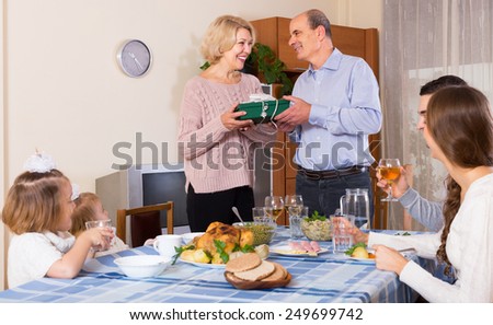 Smiling man congratulating heartily family member at the table at home