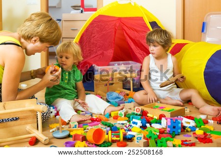Woman and two children together playing with  toys indoor