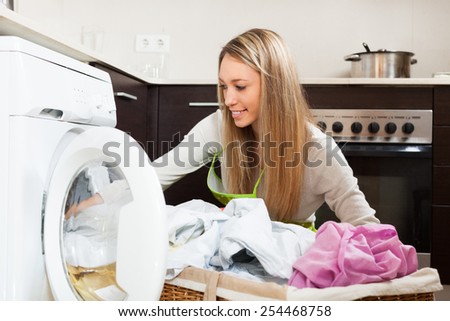 Smiling  woman working near washing machine  at home