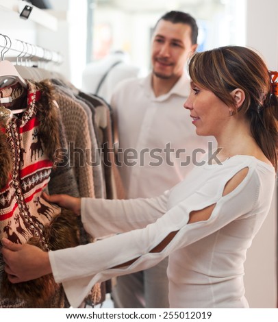Smiling couple choosing clothes at clothing shop