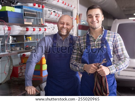 Two workmen standing near storage shelves at the auto repair shop