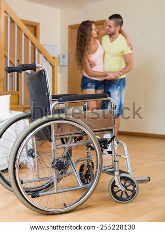 Caregiver helps handicapped girl to ambulate without invalid  chair. Focus on wheelchair