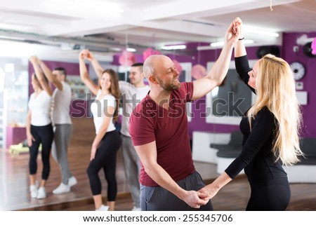 Group of cheerful smiling young adults dancing salsa in club