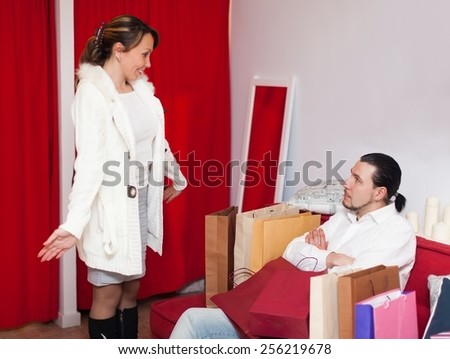 Couple choosing coat in fitting-room at fashion boutique