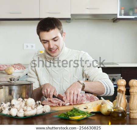 man cooking french-style meat at kitchen. Hands cutting meat