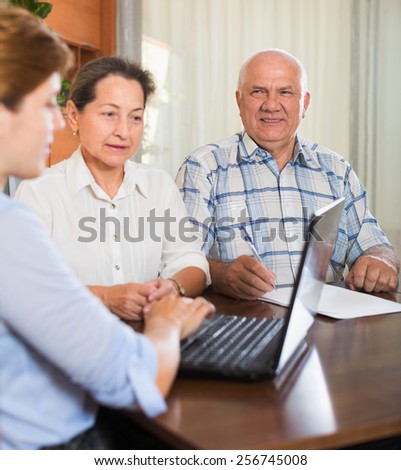 Mature couple answer questions of agent  with laptop in home