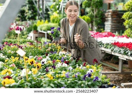 Foto Bild Weiblicher Kunde wählt Blumen im Gewächshaus