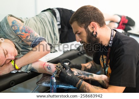 BARCELONA, SPAIN - OCTOBER 3, 2014: Professional artist  doing   tattoo on client arm. The 17th edition of The Barcelona Tattoo Expo in Fira de Barcelona