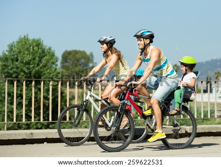 Young family of four people with bikes in sports helmets outdoors