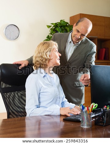 Ordinary office scene with two mature and happy co-workers