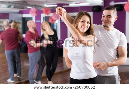 Two young smiling couples having dancing class in club