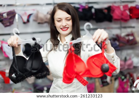 Brunette long-haired girl choosing  bra at clothing store