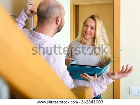 Man talking with smiling employee with paper in door