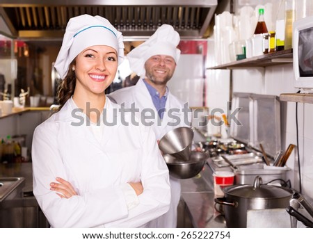 Young female cook cooking at professional kitchen in the take-away  restaurant