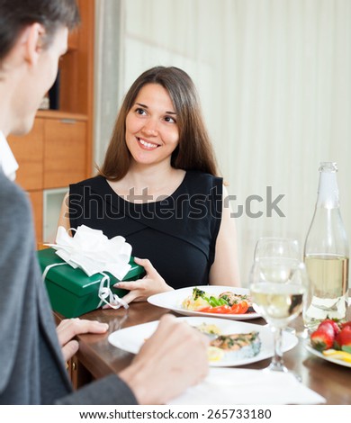 Woman giving present to man at table
