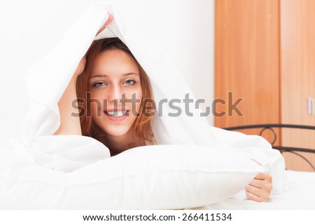 Smiling red-haired woman under the white sheets in bad at home
