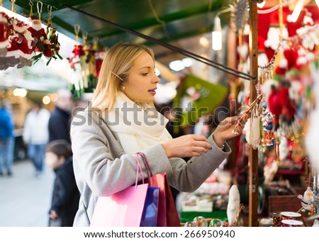 Portrait of blonde female customer near counter with Christmas gifts